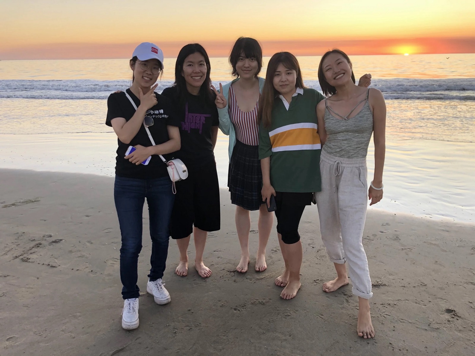 Five ISMP students standing together on the beach at sunset