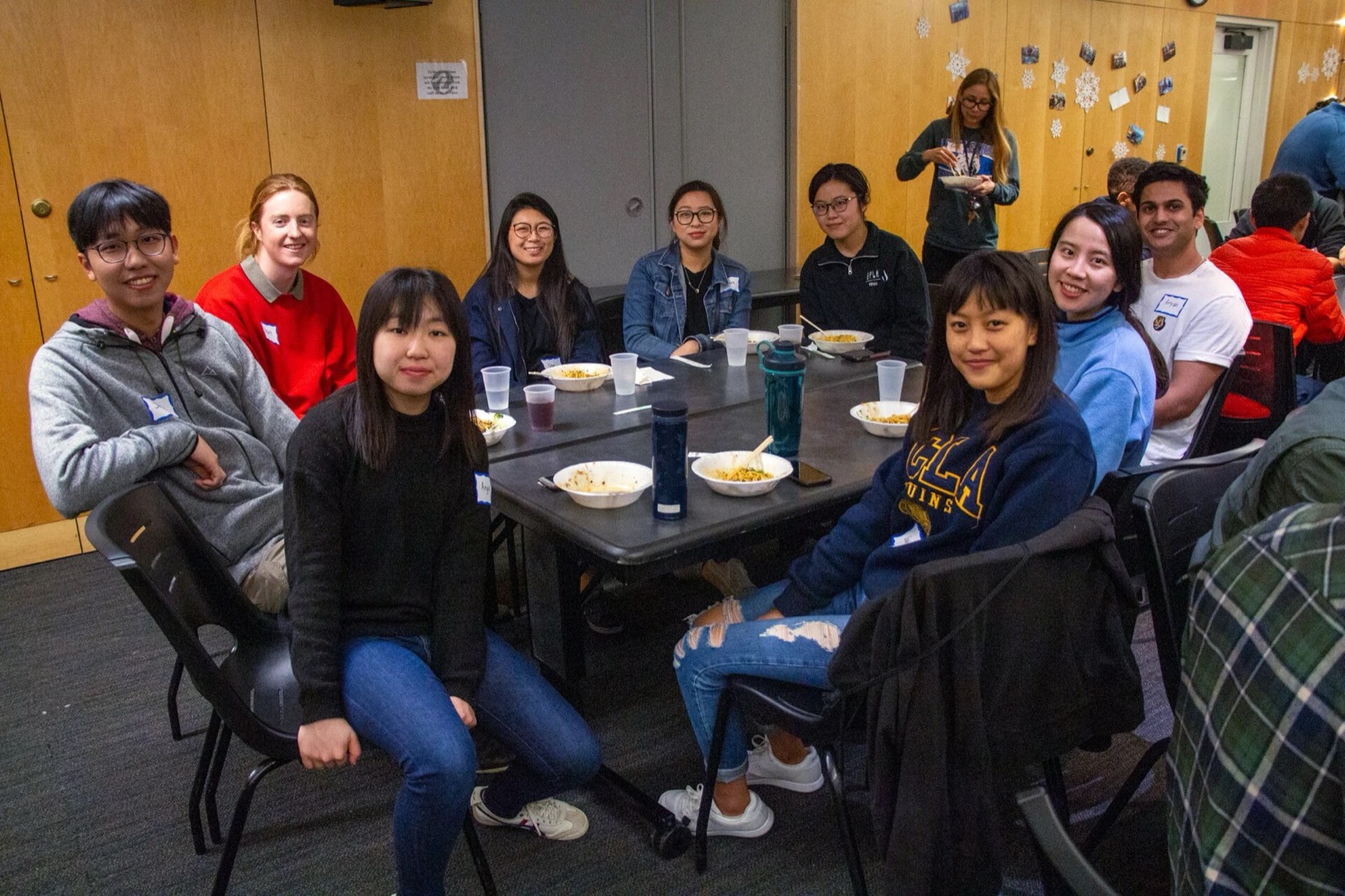 ISMP students and mentors wearing name tags, sitting around a long table over a shared meal